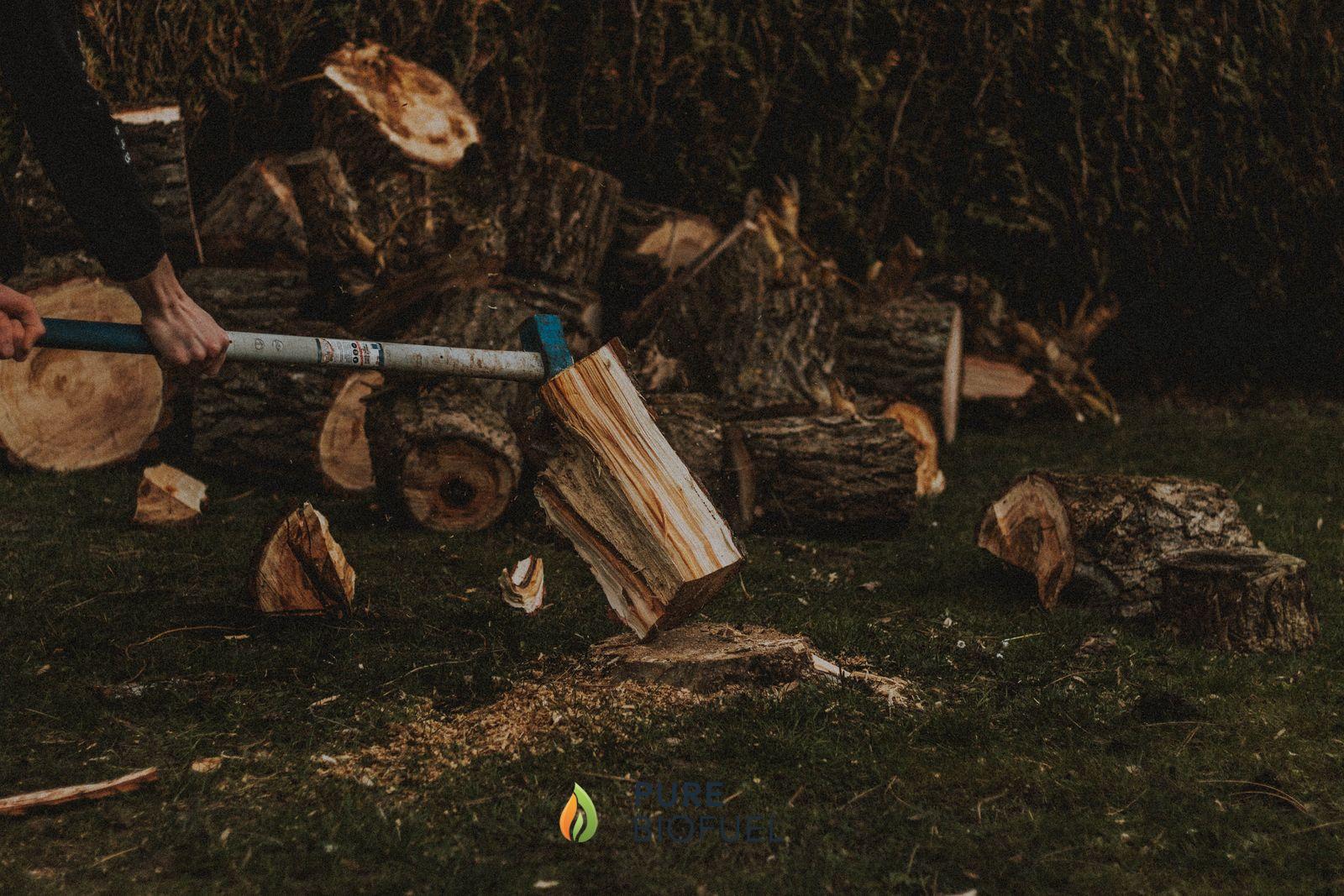 Man splitting firewood logs outdoors next to a pile of logs